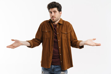 Perplexed young unshaven man showing and holding copyspace