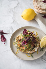 Gravlax Graved Lachs auf Knäckebrot mit Rote Beete Blätter Salat, Dill, Fischkäse, Skandinavische Senf Soße, Zitrone auf hell Marmor Hintergrund mit Leinen Tuch als Vorspeise oder Snack