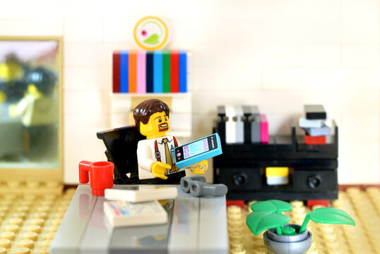 Lego minifigure in office is working on the table. Editorial illustrative image of business ocuupation.