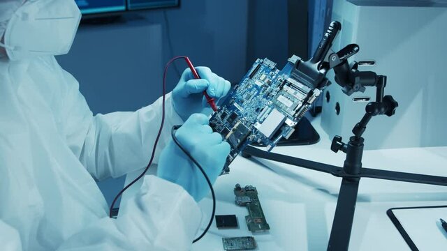Microelectronics engineer works in a modern scientific laboratory on computing systems and microprocessors. Electronic factory worker is testing the motherboard and coding the firmware.
