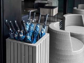 Many blue folded umbrellas in umbrella stand container box stored service.