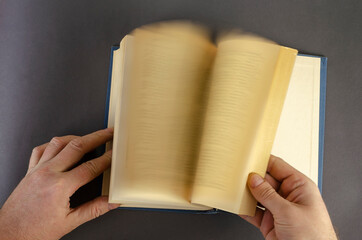 Blurred Motion Of Hand Turning Page Over gray Background.