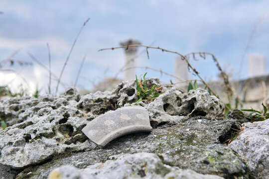 shard of ancient ceramics on a stone against a background of blurry ancient ruins
