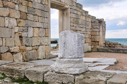 fragment of a column among the ruins of antique greek temple on the seashore