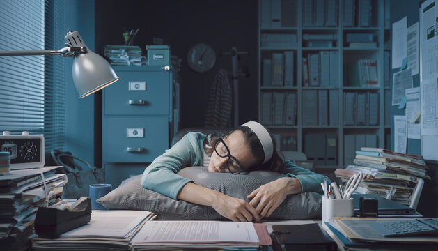 Exhausted office worker sleeping at her desk