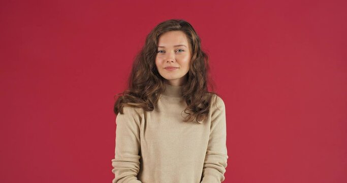 Cute pretty caucasian woman young girl model showing okay sign over red studio background. Positive lady smiles to camera with ok gesture great solution symbol. Success concept. Body language.