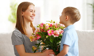 Fototapeta na wymiar Smiling boy giving flowers to woman on Mothers Day