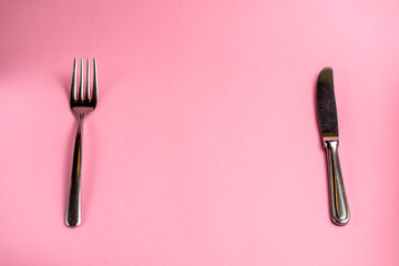 Knife and fork isolated on pastel pink background. Copy space banner
