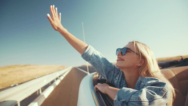 Happy woman in sunglasses enjoys life, ride in cabriolet raising her hands to sky. Concept wonderlust