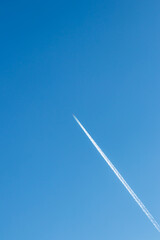 Flying airplane on a journey through the blue sky with a long white smoking exhaust plume and jetwash shows international transportation and globalization transatlantic holidays with pilots