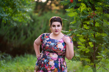 Plus size model in floral dress outdoors, beautiful fat woman with big breasts in nature