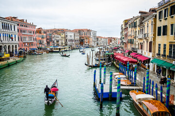 Gondola with people sails on Grand Canal in sunny Venice. Gondola is a most attractive tourist transport of Venice. 
