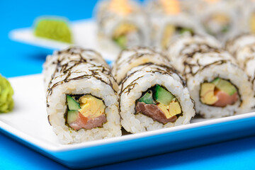 Sushi large set served on a white plate over blue background. Traditional Asian Japanese cuisine concept.