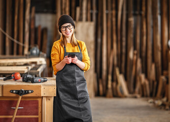 Female joiner using smartphone in workshop
