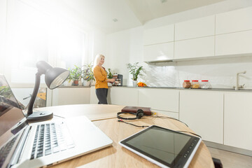 Remote working from home. Young woman using laptop. Freelancer workplace in kitchen office. Teleworking in isolation, female business, shopping online. Student in distance learning. Lifestyle moment.