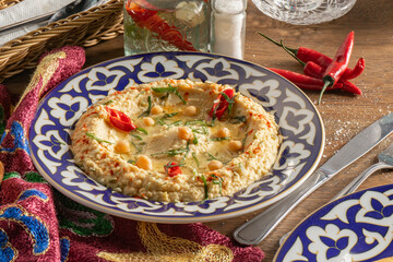 Hummus with chili pepper in a plate with a traditional Uzbek ornament