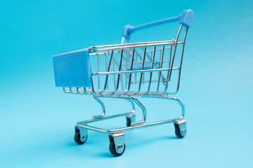 Shopaholic. Buyer. Shopping concept. Close-up. Isolated shopping trolley on a blue  background. 