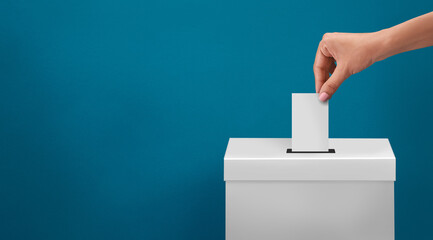 Obraz premium female or women Voter Holds Envelope In her Hand Above Vote Ballot for casting vote on blue background
