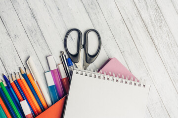 notepads colored pencils markers scissors on a wooden table school office