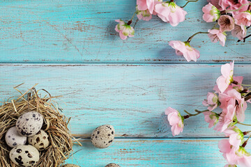 quail easter eggs and spring flowers on wooden background. copy space for text