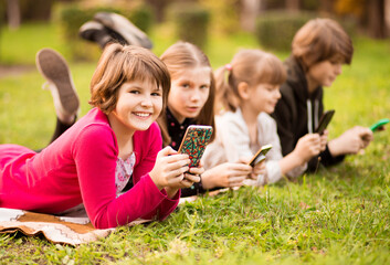 Outdoor portrait of little girls and boys playing with phones . High quality photo