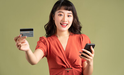 Asian woman holding a bank card and staring at her phone