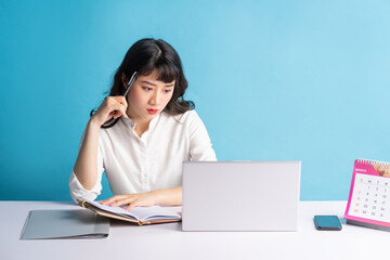 Young Asian buisness woman working on blue background