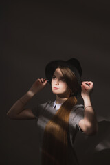 Girl in a strict gray dress and black hat with narrow brim