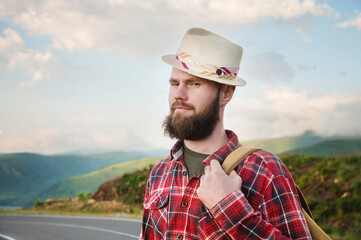 Portrait of a sly cheerful bearded Jewish man hitchhiker in a hat and shirt against the backdrop of...