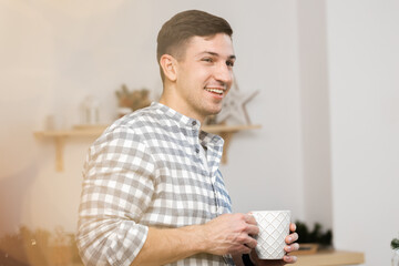 Young man drinking hot drink in kitchen