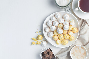 Sweet, airy meringues in white and yellow, with a cup of tea.