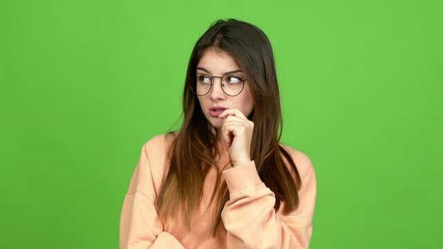 Young caucasian woman with glasses having doubts over isolated background. Green screen chroma key