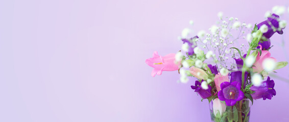 Fototapeta na wymiar spring bouquet of purple and pink bell flowers over purple wooden background