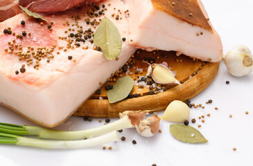 raw pork meat and lard with salt, spices and garlic on a cutting board, white background