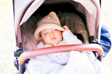 six month old baby napping in a stroller with sun hat. baby dream concept. plans with baby