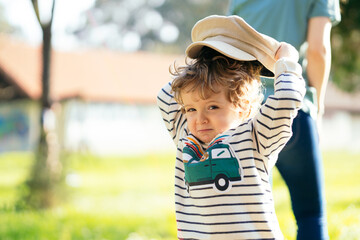 two-year-old boy playing with a hat in a park in spring. lifestyle concept © Patricia