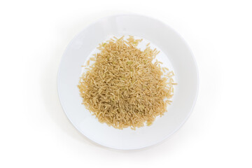 Uncooked brown rice on white dish, top view