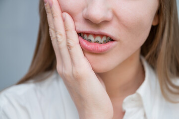 Fototapeta premium Close-up portrait of a red-haired girl suffering from pain due to braces. Young woman corrects bite with orthodontic appliance.