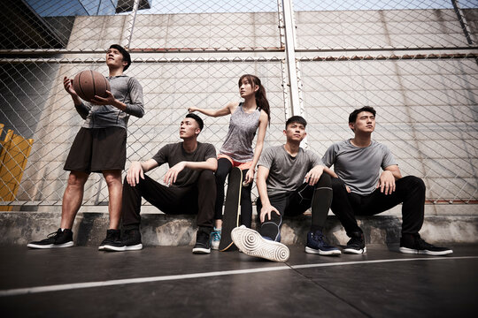 asian young adults resting relaxing on outdoor basketball court