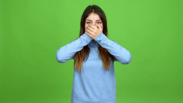 Young caucasian woman covering mouth with hands. Can not speak over isolated background. Green screen chroma key