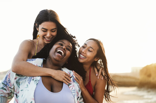 Happy multiracial friends having fun on the beach during summer holidays