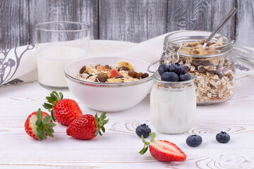 Healthy breakfast with homemade yoghurt and fresh strawberries and blueberries, muesli on a white wooden table in rustic style, close up, horizontal