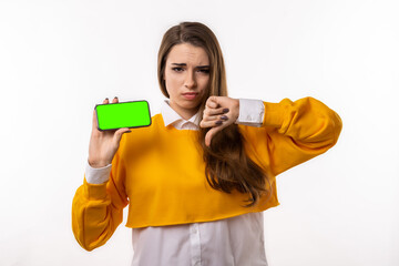 Pretty young brunette woman in casual clothes is showing smartphone blank screen in her hand