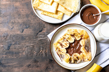 Crepes, thin pancakes on a plate. Chocolate hazelnut spread and banana filled crepes on plate....