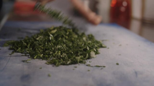 French chef prepare vegetables on a cutting board. Chopping parsley in gastronomic restaurant. 