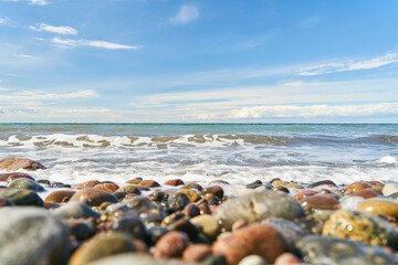 Pebbles on the beach by the sea with waves and sky