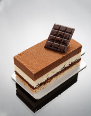 Chocolate and vanilla layers cake with small piece of dark chocolate on the top. French confectionery concept.