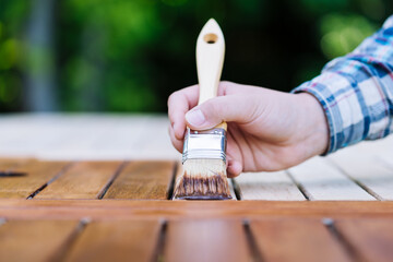 young woman painting wooden exotic wood table in the garden with a brush - shallow depth of field - 418874460
