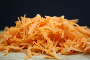 Grated orange carrots on a black background.