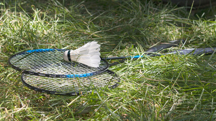 Badminton on the grass. White feather shuttlecock and rackets in sunlight. Summer sport leisure. Format 16:9